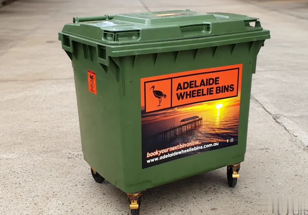 An Adelaide Wheelie Bins 1100 litre green bin with the orange ibis sticker and the Port Adelaide sunset print